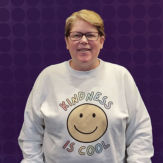 Smiling woman in sweatshirt that says "kindness is cool"