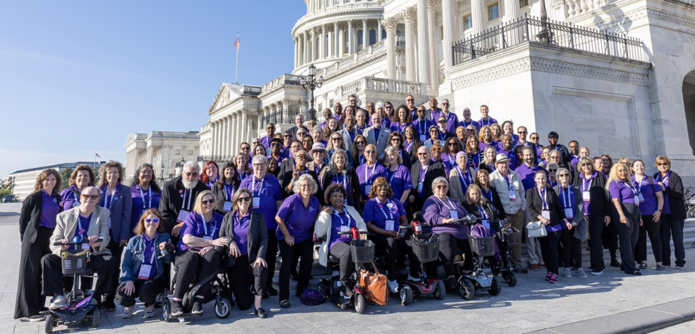 Large group of people standing in front of the US capitol building pose for a group photo